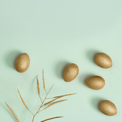 Easter background with bright eggs, shiny golden colored eggs and decorative herb on green paper