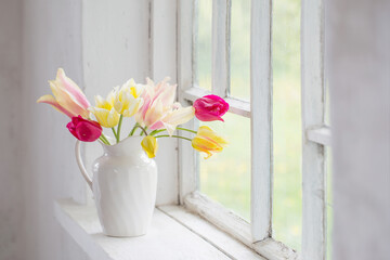 beautiful tulips in vase on white windowsill