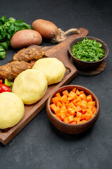 Half shot of tasty cutlets with vegetables and a bunch of green on dark table