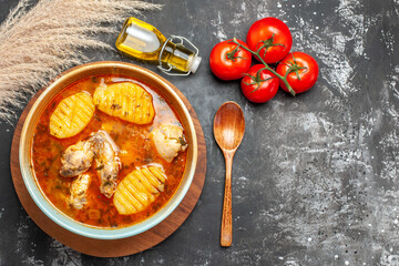 Chicken meal fallen oil bottle spoon and tomatoes on dark background