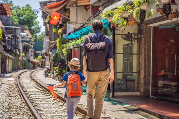 Obraz na płótnie Canvas Father and son travelers walk around railway paths which go through residential area in Hanoi city. Hanoi Train Street is a famous tourist destination. Vietnam reopens after coronavirus quarantine