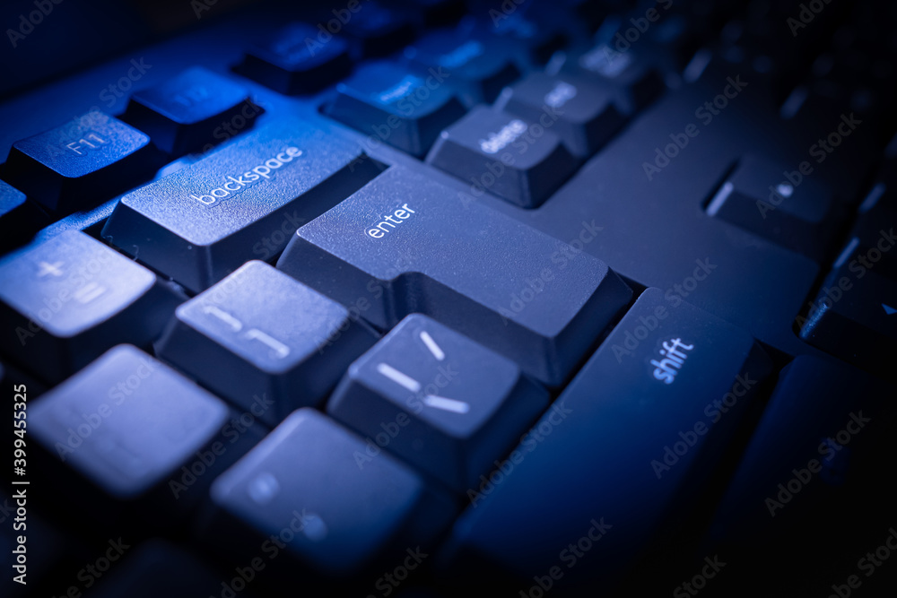 Poster black computer keyboard. the backspace, enter, and shift keys are illuminated. close-up of computer 