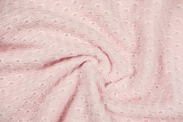 pink knitted fabric swirl. twisted soft sweater textured background. pink female textile. winter outfit cozy pullover.