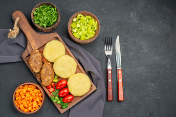 Dinner preparation for tasty cutlets vegetables and greens on dark background
