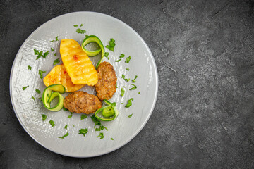 Tasty dinner with cutlet meal along with potatoes on a white plate on dark table