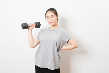 Beautiful young Asian woman lifting dumbbells smiling and energetic isolated over white background. Healthy lifestyle.