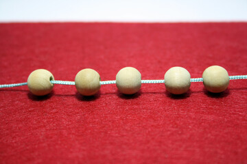 Wooden beads on a thread on a red background.