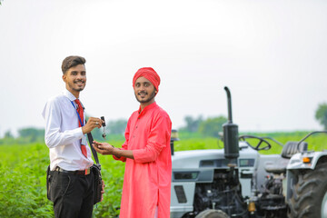 Young indian banker give a new tractor key to farmer at agriculture field