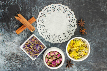 top view of bowls of dry flower with a piece of lace on grey background