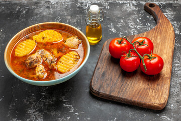 Top view of chicken soup fresh tomatoes on wooden cutting board
