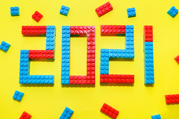 New year, 2021. Lettering from a children's constructor on a yellow background. Toys in isolation. copy space. The concept of a hobby and learning