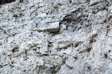mountain textures of stones with interlayers of gypsum, colored quartz, clay, sand and other layers of various ores, with different textures, color and density, in gypsum ore quarry.