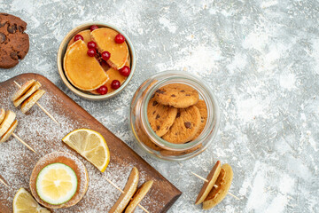 Buttermilk pancakes with lemons on wooden cutting board and cookies sweeties on blue background