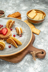 Vertical view of homemade pancakes and biscuits on wooden cutting board on blue backgound