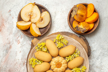 a plate of cookies on wooden platter and bowls of fruits on marble background