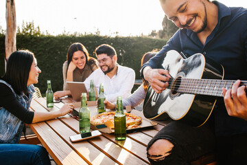 Mexican friends drinking beer on the terrace and latin man playin a guitar in Mexico city