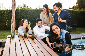 Mexican friends drinking beer on the terrace and latin woman playin a guitar in Mexico city