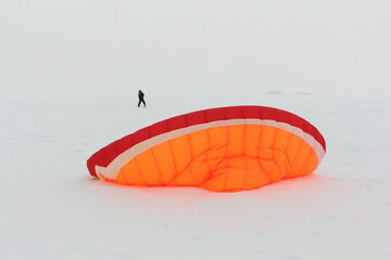 Man training with a kite in a snowstorm on  frozen river in winter, Ob reservoir, Novosibirsk, Russia
