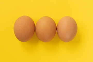 Close-up view of raw chicken eggs on yellow background.