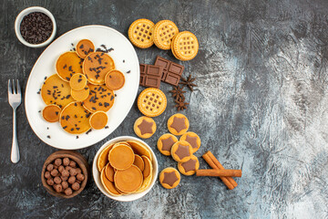top view of pancakes and different sorts of desserts on grey background