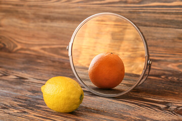 Lemon looking at its reflection in mirror on wooden background