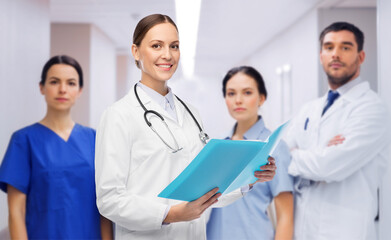 medicine, profession and healthcare concept - happy smiling female doctor in white coat with folder...