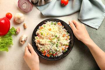 Female hands with tasty pilaf on color background