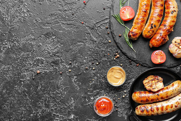 Delicious grilled sausages and vegetables on dark background