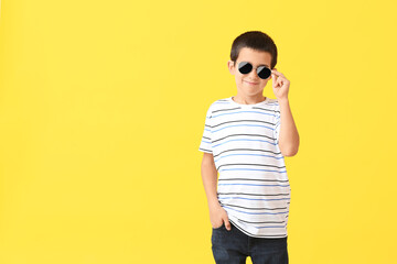 Cute boy wearing stylish sunglasses against color background