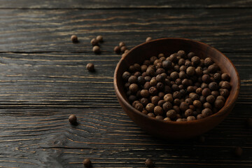 Bowl with peppercorns on wooden table, space for text