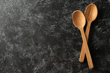 Wooden spoons on black smokey background, space for text