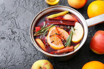 Saucepan with hot mulled wine on dark background