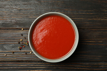 Bowl of tasty tomato soup on wooden background