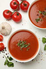 Bowls with tomato soup and ingredients on white background