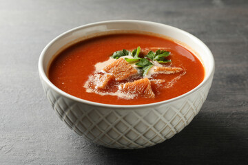 Bowl of tasty tomato soup on dark wooden background