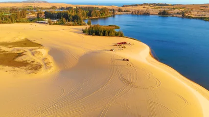 Fotobehang Oranje Aerial view of Bau Trang lake (raw of automobiles with blue sky in desert, beautiful landscape of white sand dunes), the popular tourist attraction place in Mui Ne, Vietnam.  © CravenA