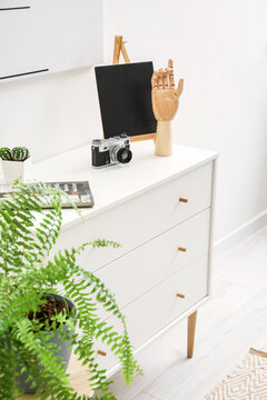 Wooden hand and photo camera on chest of drawers in interior of room