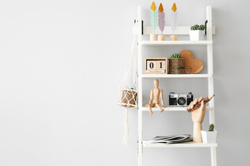 Wooden hand and mannequin with stylish decor on shelving unit in interior of room