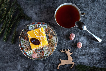 New Year's photo of a cake with tea, dried kumquat on a table with fir branches and toys, postcard