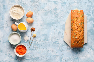 Baked pumpkin pie with ingredients on color background