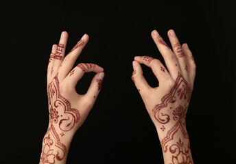 Beautiful female hands with henna tattoo on dark background