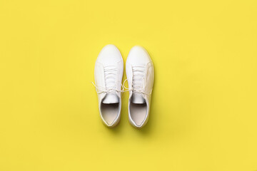 Stylish white sneakers on yellow background. Minimal flat lay. Demonstrating trendy Color of the Year 2021. Illuminating Yellow and Ultimate Gray