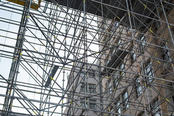 Extensive scaffolding providing platforms for work in progress on a tall building under construction with scaffolds.