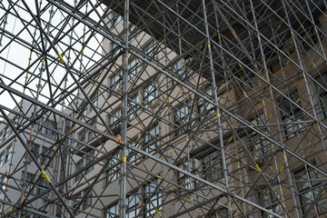 Extensive scaffolding providing platforms for work in progress on a tall building under construction with scaffolds.
