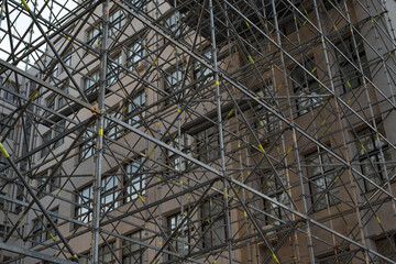 Extensive scaffolding providing platforms for work in progress on a tall building under construction with scaffolds.