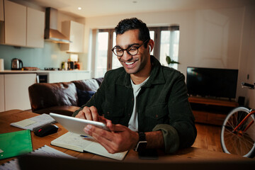 Smiling mixed race businessman face timing family from digital tablet feeling happy sitting at desk 
