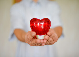 a man holds a heart in his hands as a symbol of care, love, happiness, and health