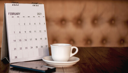 Calendar, mobile, coffee cup Placed on an old wooden table is a planning idea for success.