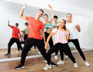 Cheerful happy positive smiling teenage boys and girls having fun in choreography class, posing with female trainer