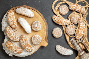 Variety of delicious cookies on rope and brown broken cutting board with ancient pottery on black table